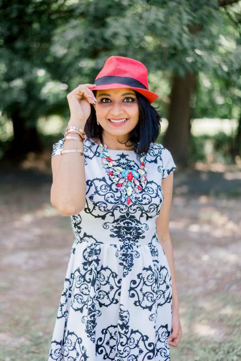 Kash smiling and tipping a red hat